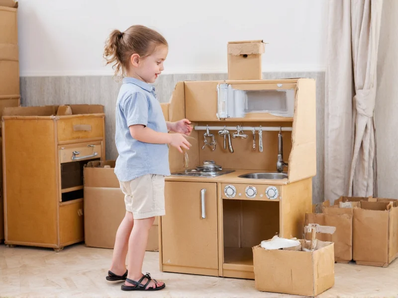 Children playing with cardboard play kitchen construction