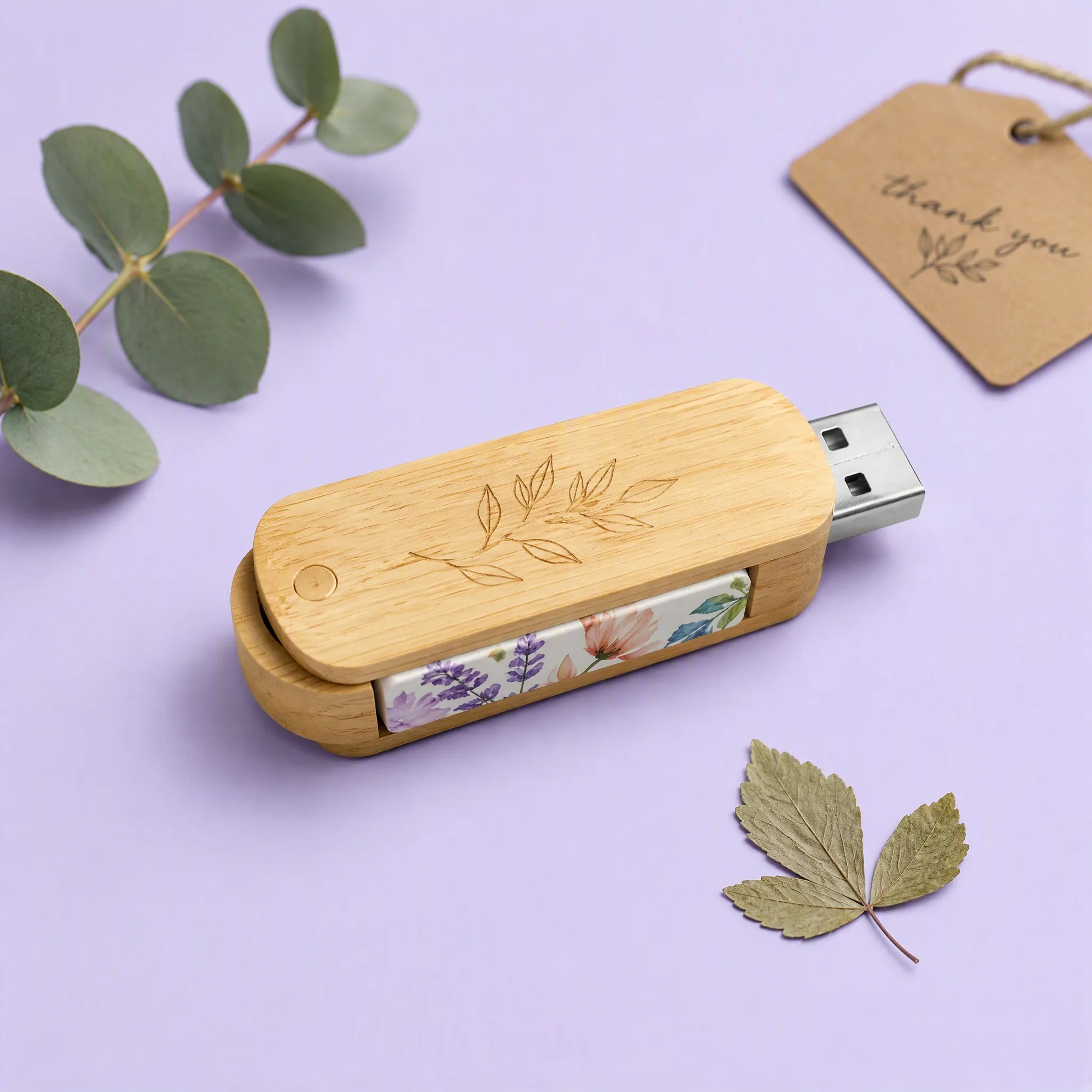 Natural Bamboo Wood Swivel USB Flash Drive with Botanical Olive Branch Engraving beside Kraft Thank You Tag and Eucalyptus