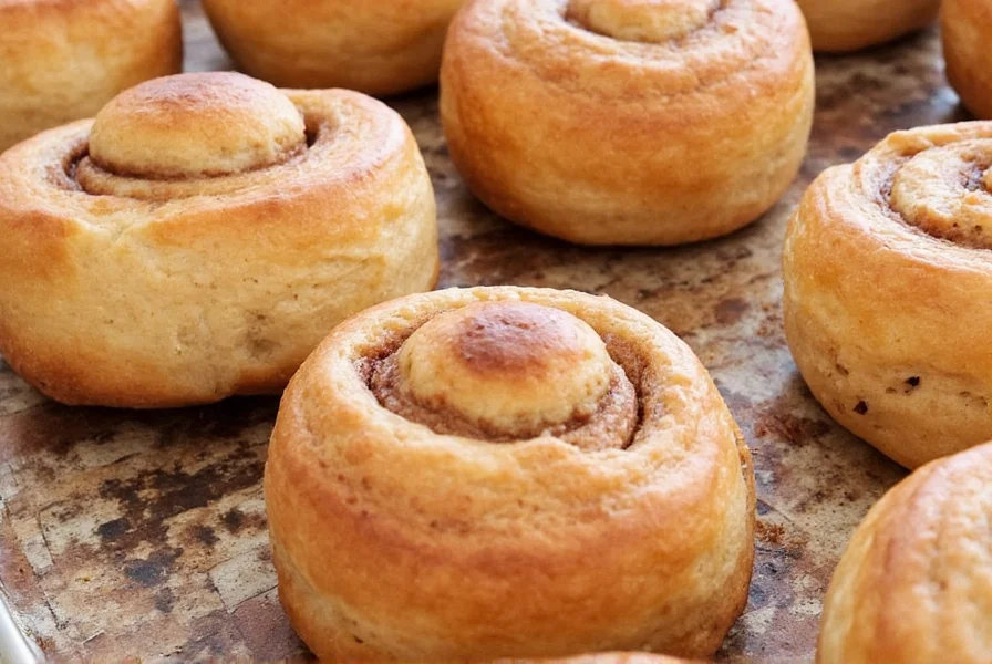 Swedish fika setting with kanelbullar, coffee cup, and cloudberry jam on a wooden table