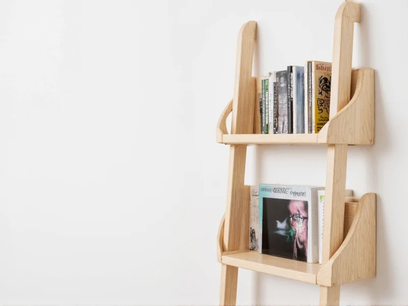 DIY wooden ladder bookshelf against white wall