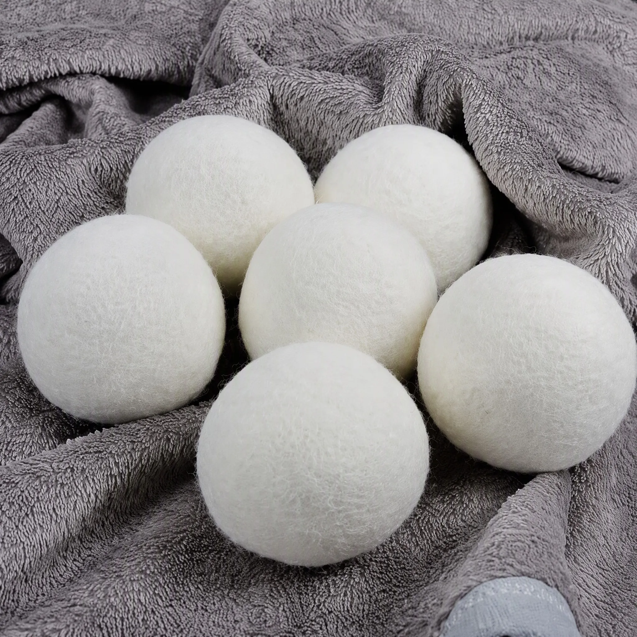 Close-up of New Zealand wool laundry balls on a grey towel showing the felted surface texture