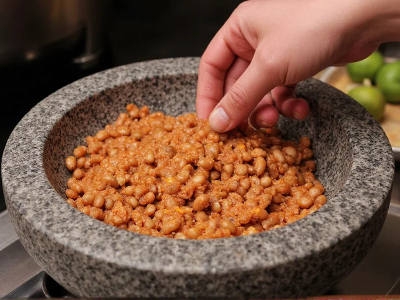 Hand mashing refried beans in traditional molcajete
