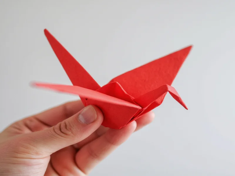 Hand holding recycled paper origami crane