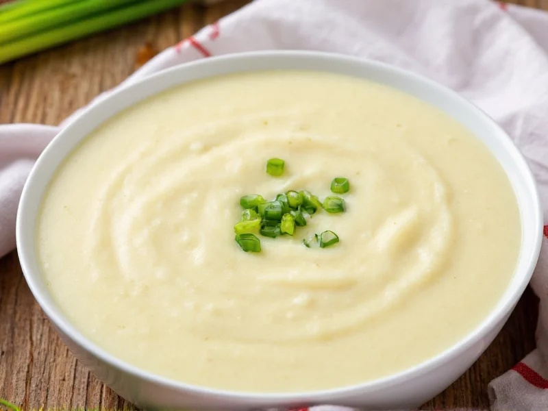 Creamy potato soup in white bowl with chive garnish