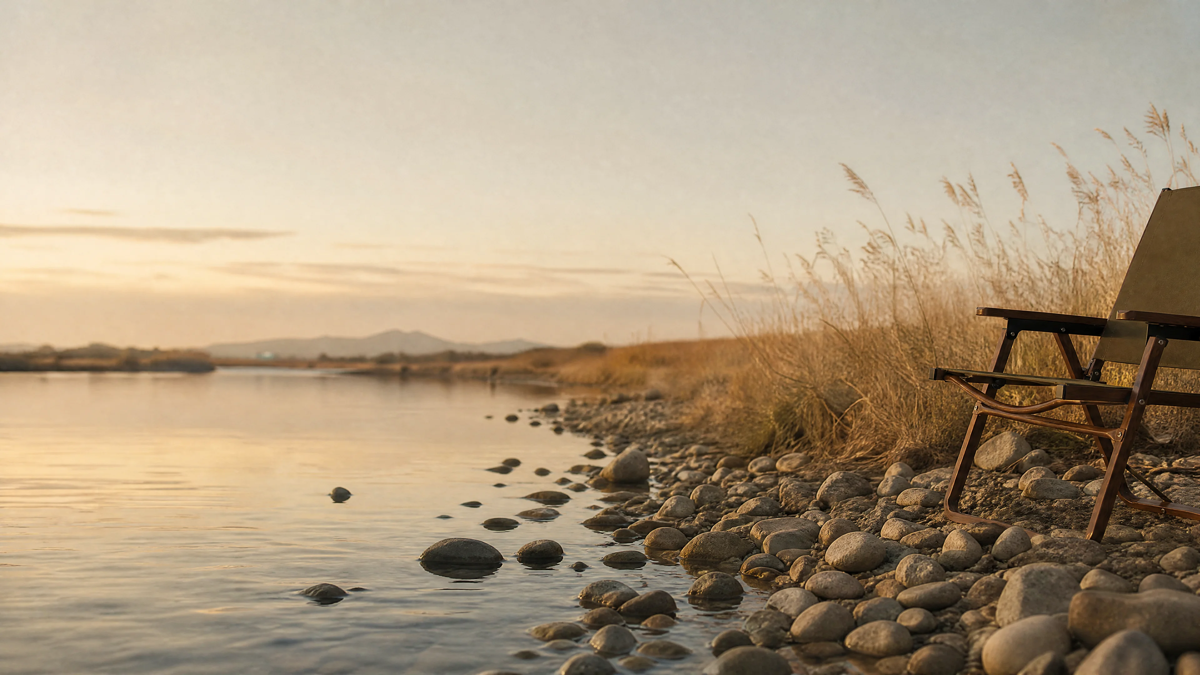 SummitSage Heritage Wood-Grain Aluminum Chair resting on a pebbled lakeshore at golden hour