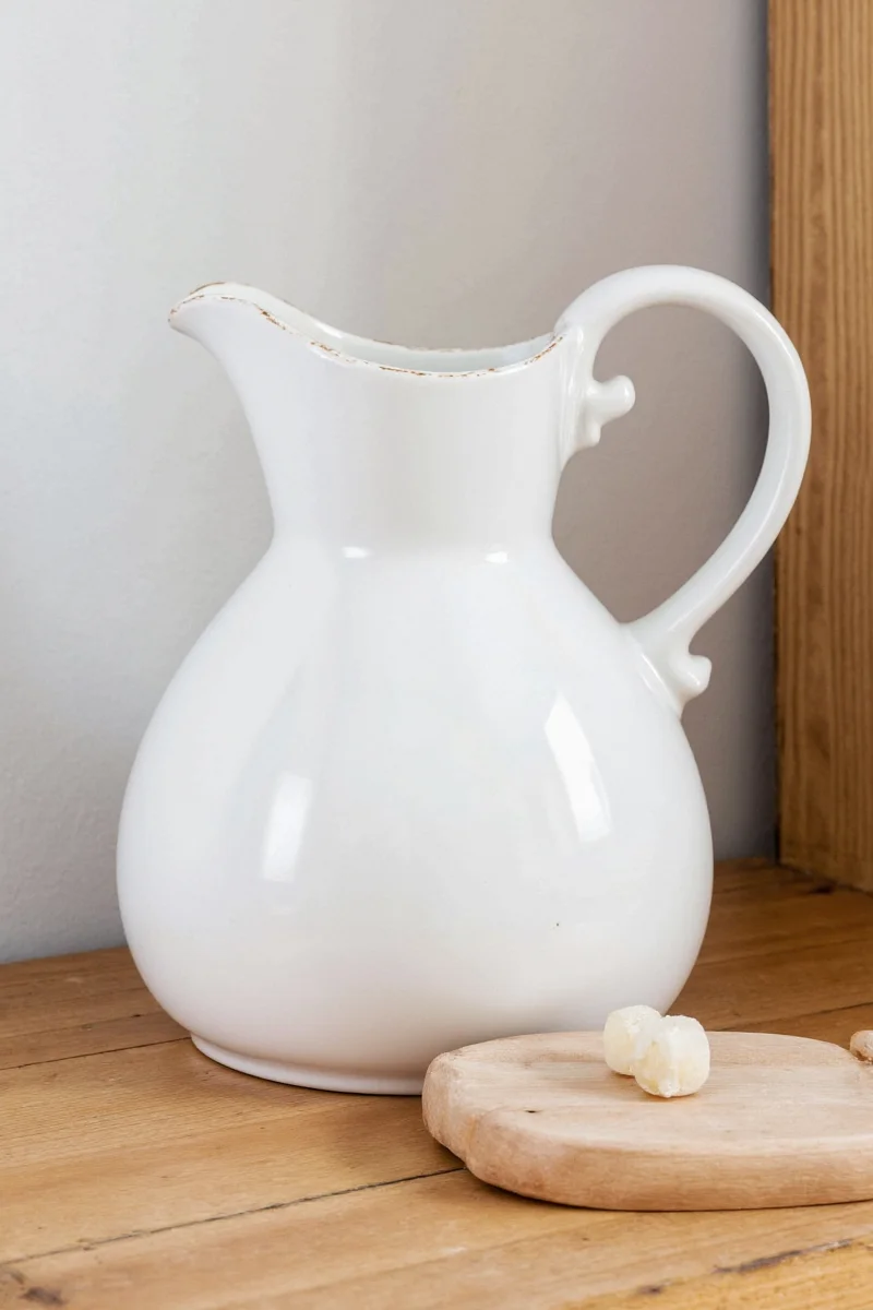 A vintage-style ceramic bunny rabbit pitcher with pastel pink ears sitting on a wooden kitchen counter.