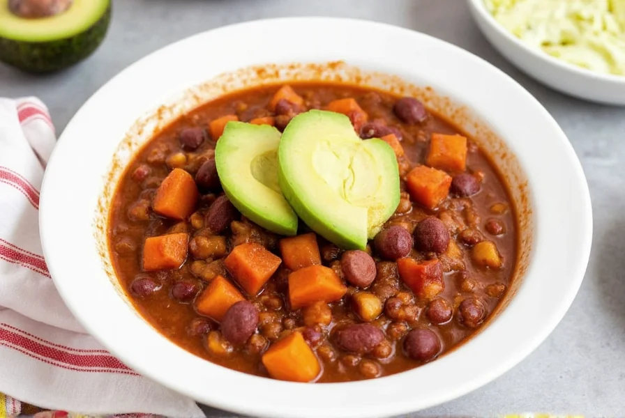 Finished slow cooker sweet potato chili in white bowl with avocado garnish