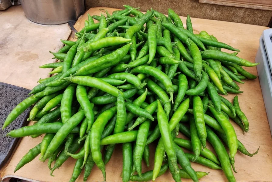 Freshly harvested Hatch green chiles arranged on a wooden table with roasting equipment