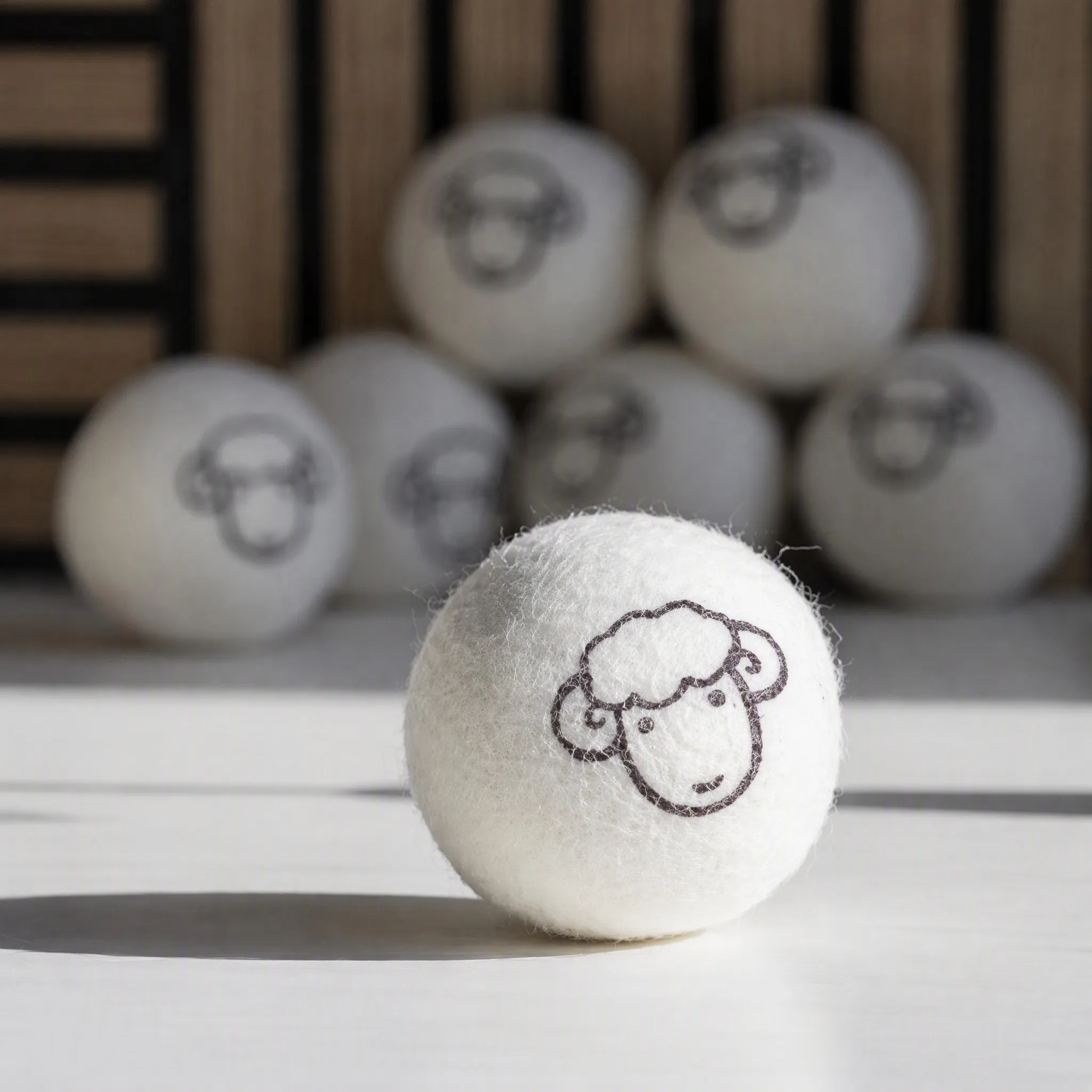 Macro view of a printed wool dryer ball showing a crisp logo print on dense felted New Zealand wool