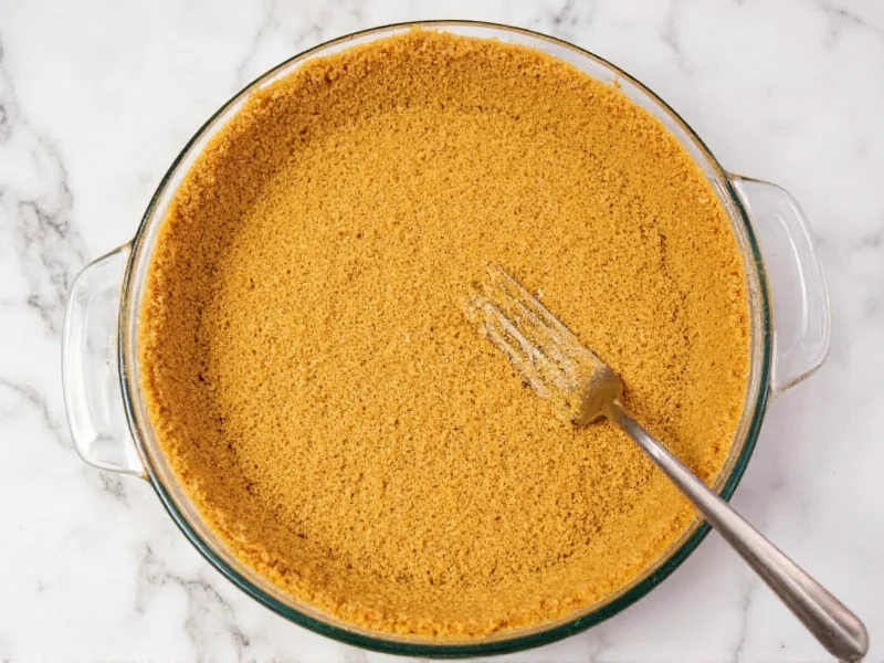 Golden graham cracker crust in glass pie pan with fork