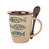Color fish painted ceramic milk coffee mug with spoon in hand