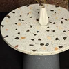Round concrete coffee table measuring 30" in diameter. Top cast with large white marble terrazzo and rests on a fluted concrete