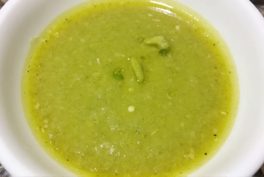 Fresh homemade jalapeno coriander sauce in a white bowl with lime wedge and cilantro garnish