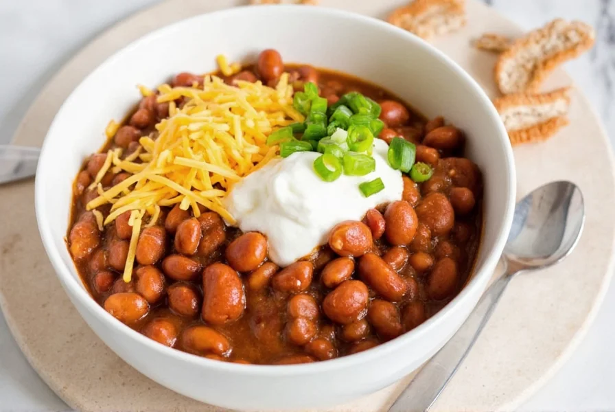 Finished bowl of easy chili beans recipe with toppings like sour cream, cheese, and green onions