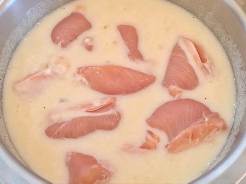 Raw chicken strips soaking in buttermilk brine