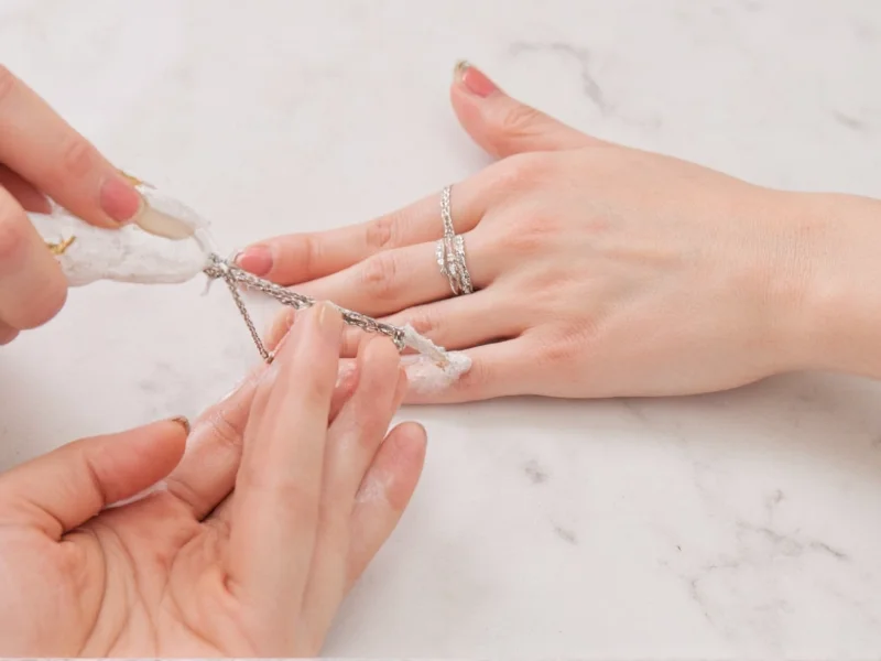Applying baking soda paste to silver jewelry