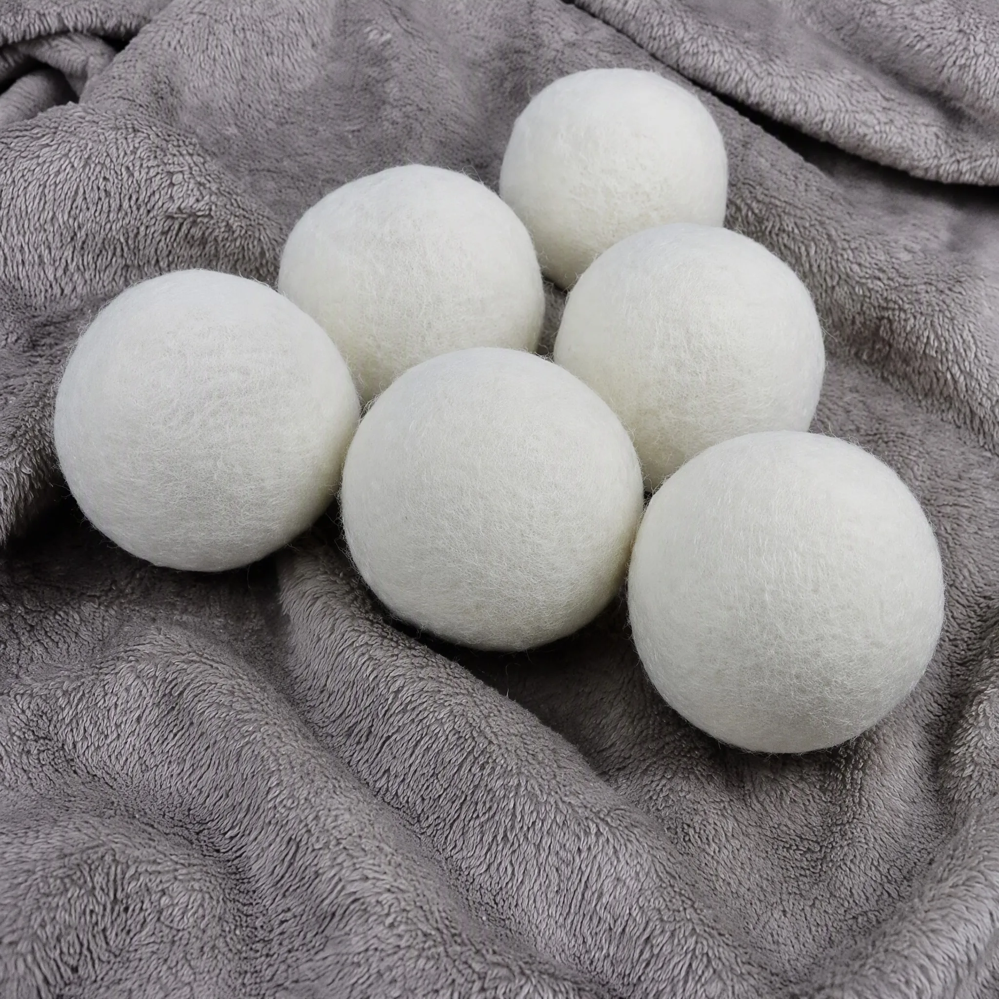 Six reusable wool dryer balls resting on a soft grey towel after tumble drying