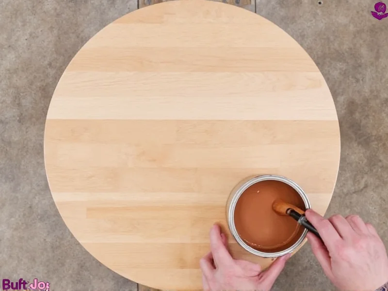 Hand applying natural wood stain to DIY coffee table surface