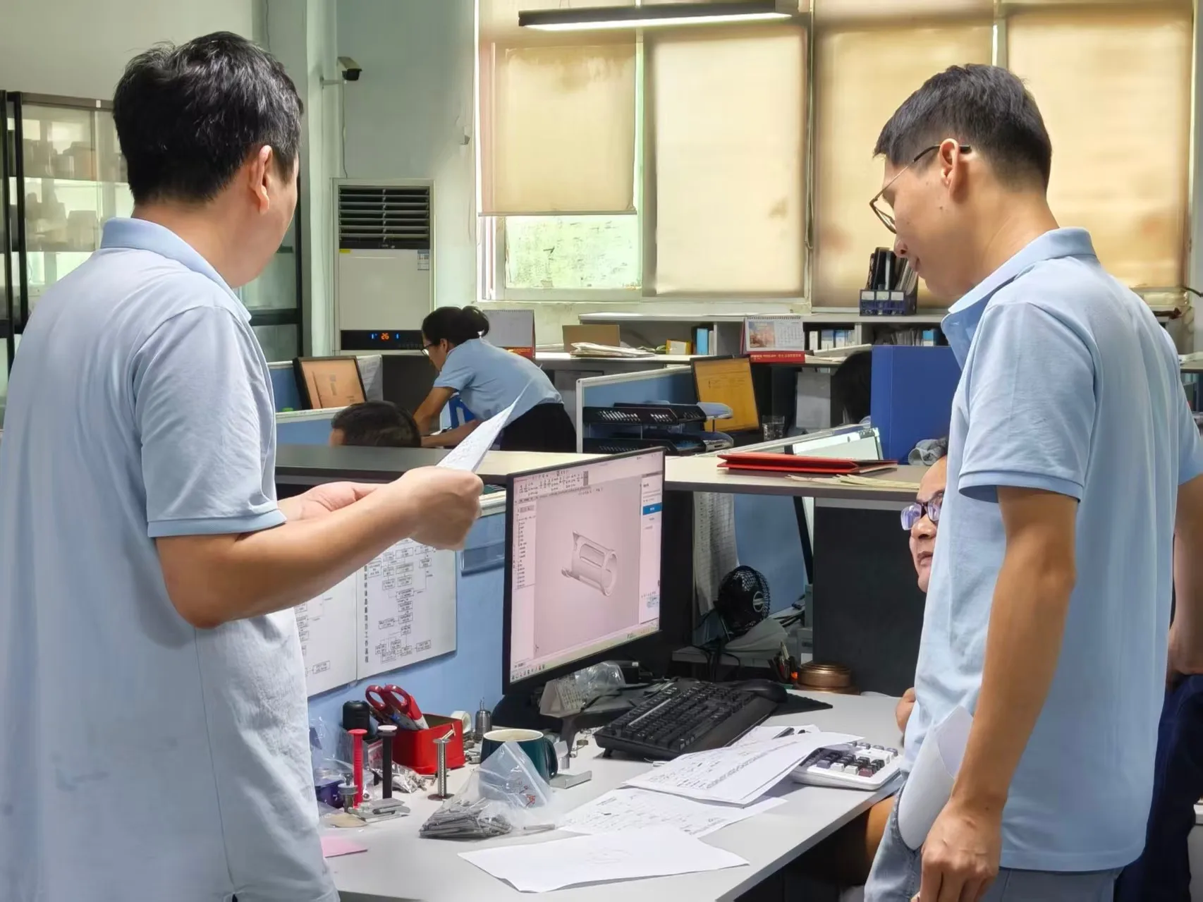 Runpeng engineers reviewing a customer's 3D CAD model and printed drawing together at a workstation