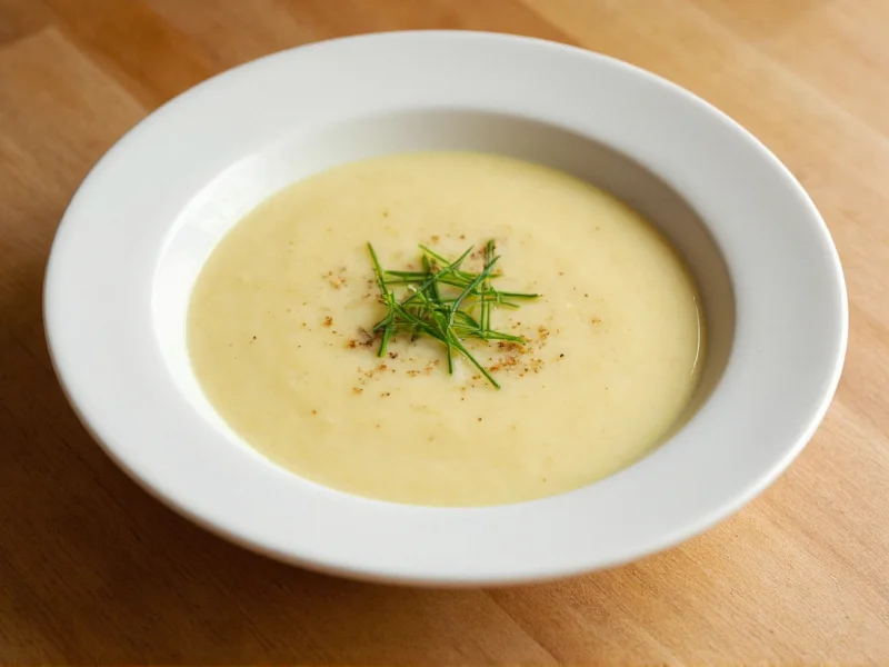 Bowl of creamy potato soup garnished with chives and black pepper