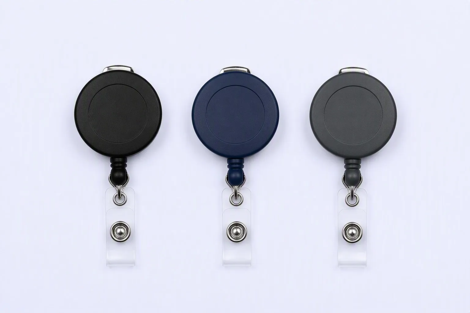 Three matte badge reels in black, navy and charcoal on a light background