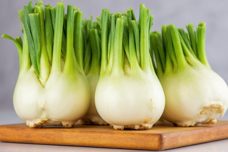 Fresh fennel bulbs with green fronds displayed on wooden cutting board
