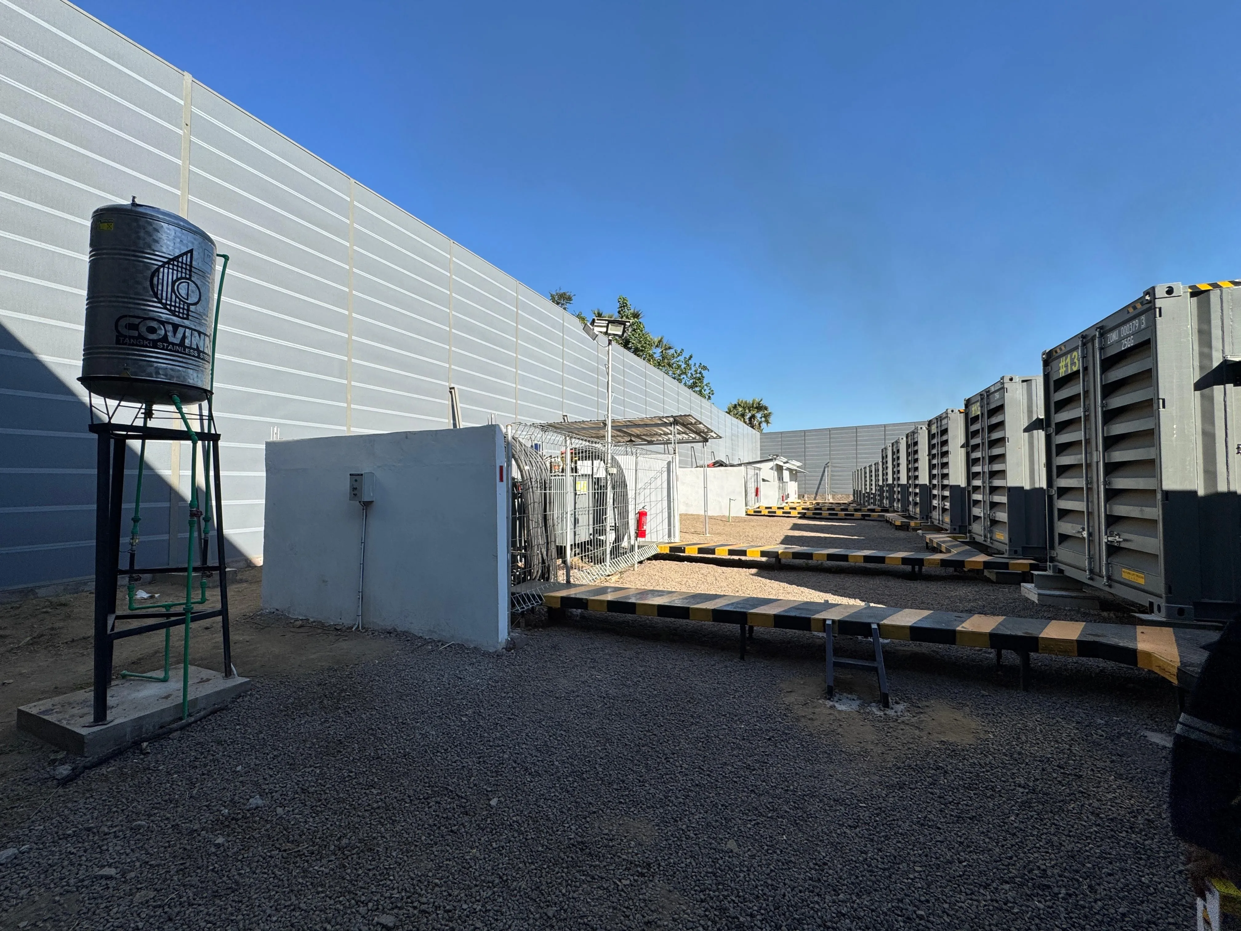 Wide view of metal noise barrier panels beside power plant generator equipment