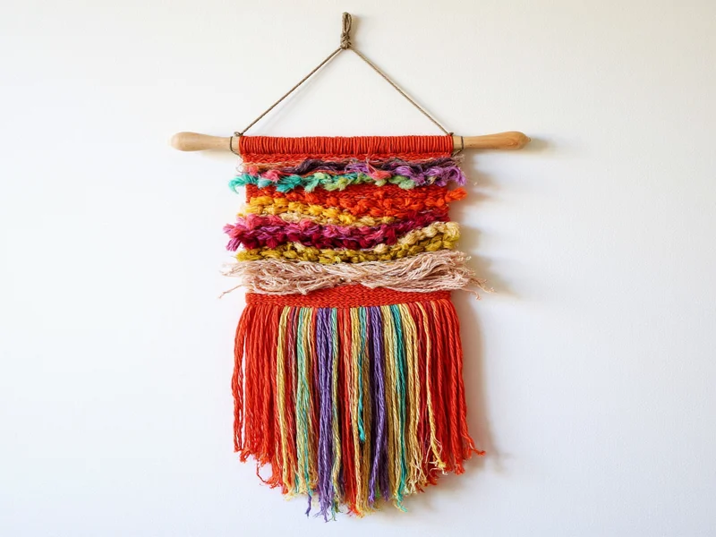 Colorful woven wall hanging made from fabric scraps on wooden dowel
