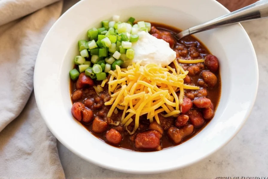 Finished crock pot chili served in white bowl with toppings including sour cream, shredded cheese, and green onions