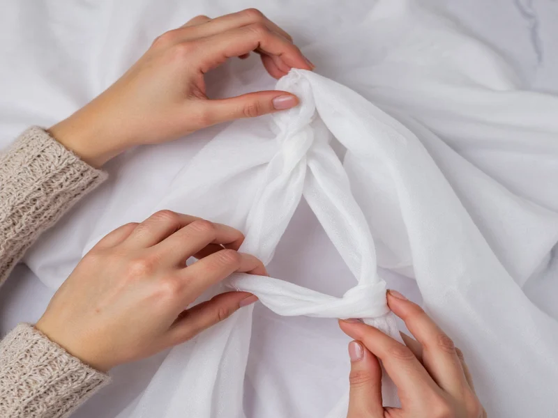 Hands tying triangular knot in white fabric for ghost craft
