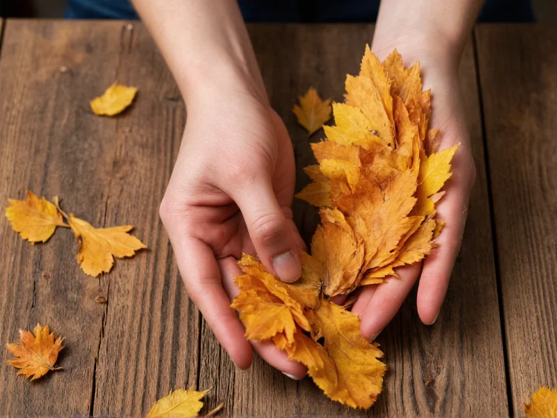 Hand arranging dried leaves on rustic wooden table