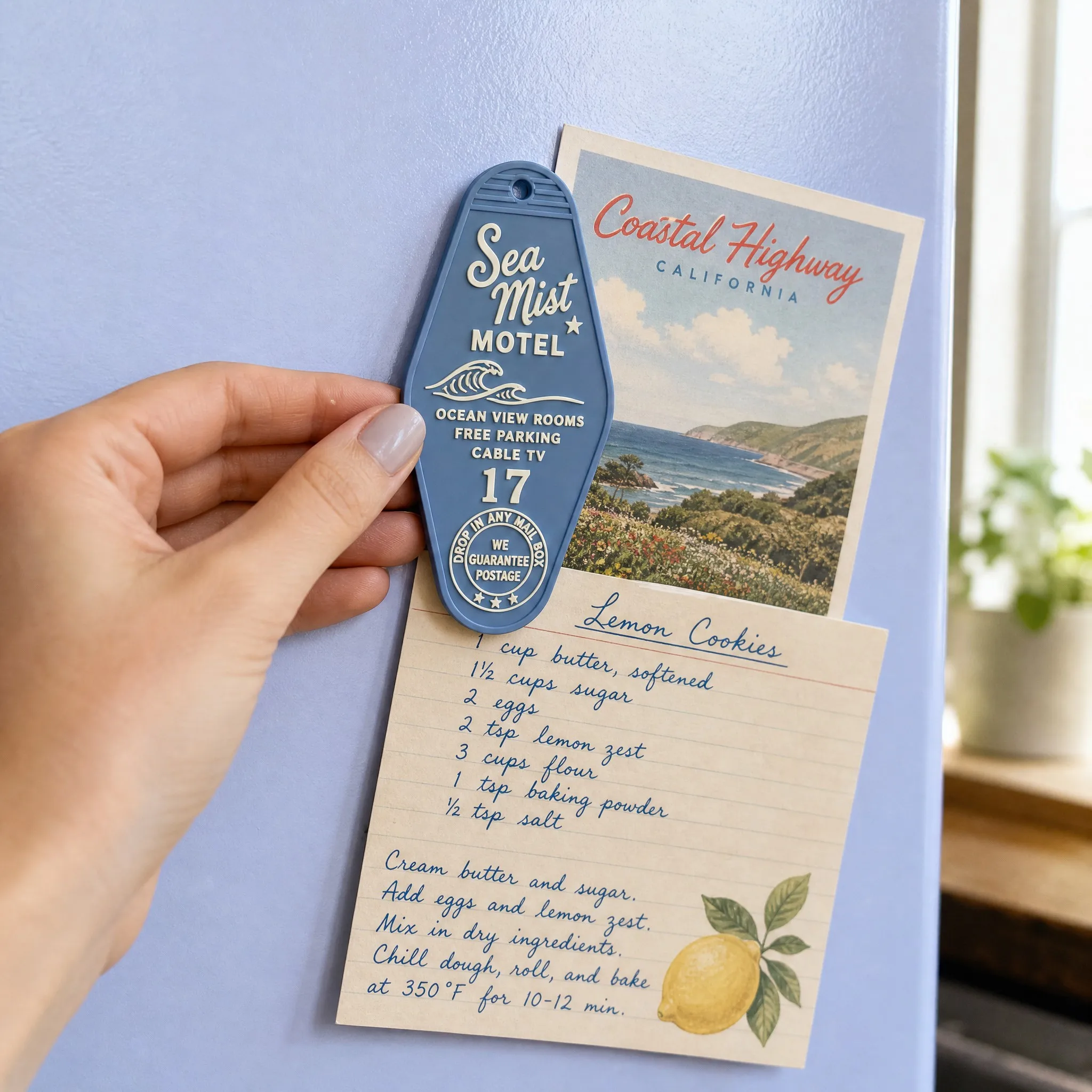 Sea Mist Motel 17 Dusty Blue Diamond Magnet Holding Coastal Postcard and Lemon Cookies Recipe