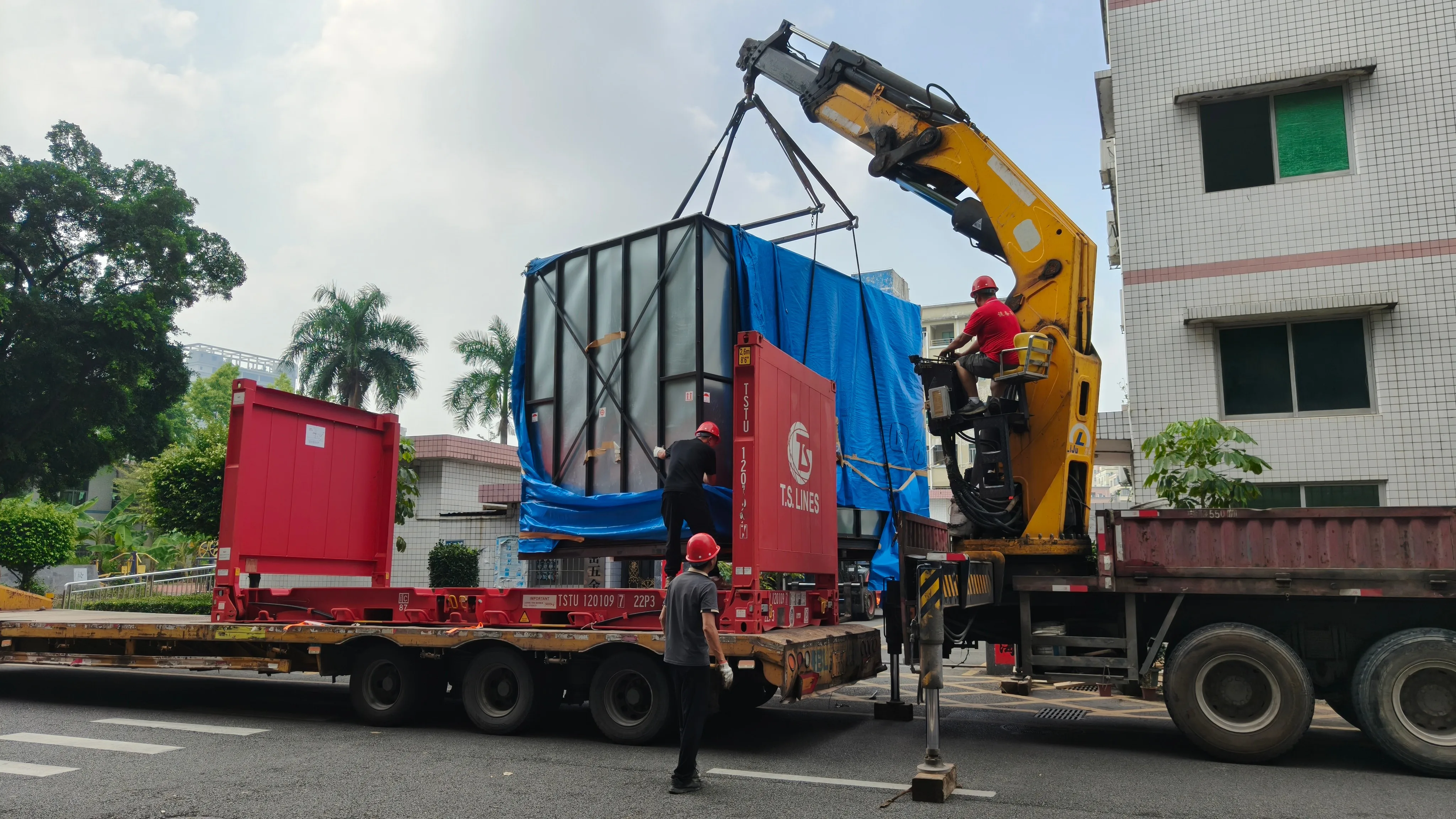 Crane lifting the crated Mazak machining center onto the factory yard