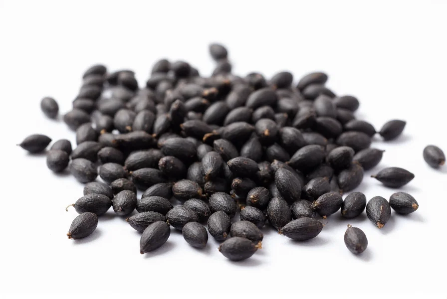 Close-up photograph of nigella seeds showing their distinctive teardrop shape and matte black color against a white background