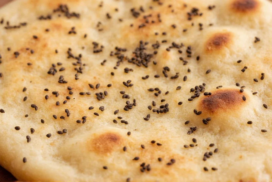 Close-up of nigella seeds sprinkled on fresh naan bread with visible texture and matte black color