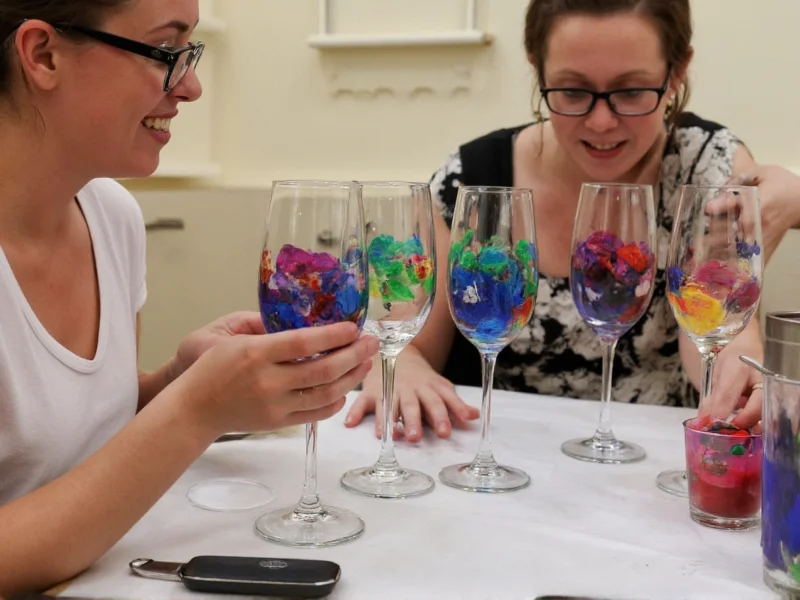 Group painting wine glasses during Cork and Craft workshop session