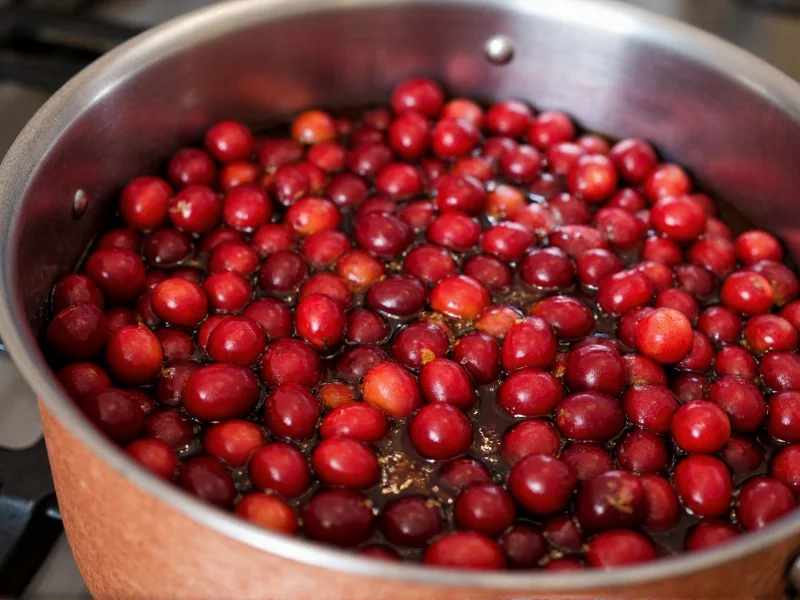 Fresh cranberries bubbling in copper pot with orange zest