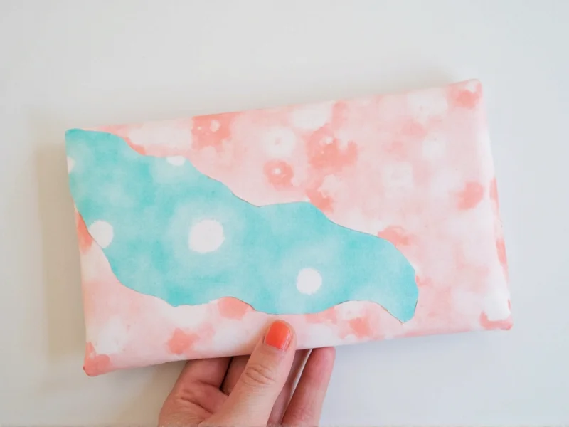 Hand holding custom DIY envelope made from recycled paper