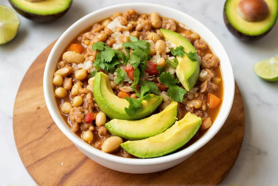 Finished white bean chicken chili served in bowl with toppings like avocado, cilantro, and lime
