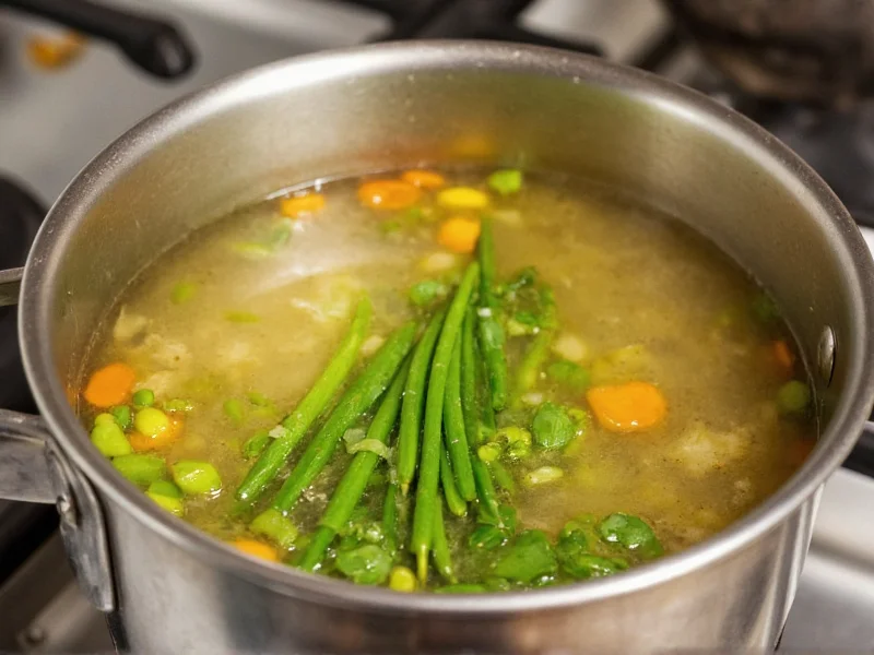 Simmering vegetable broth in stainless steel pot with herbs