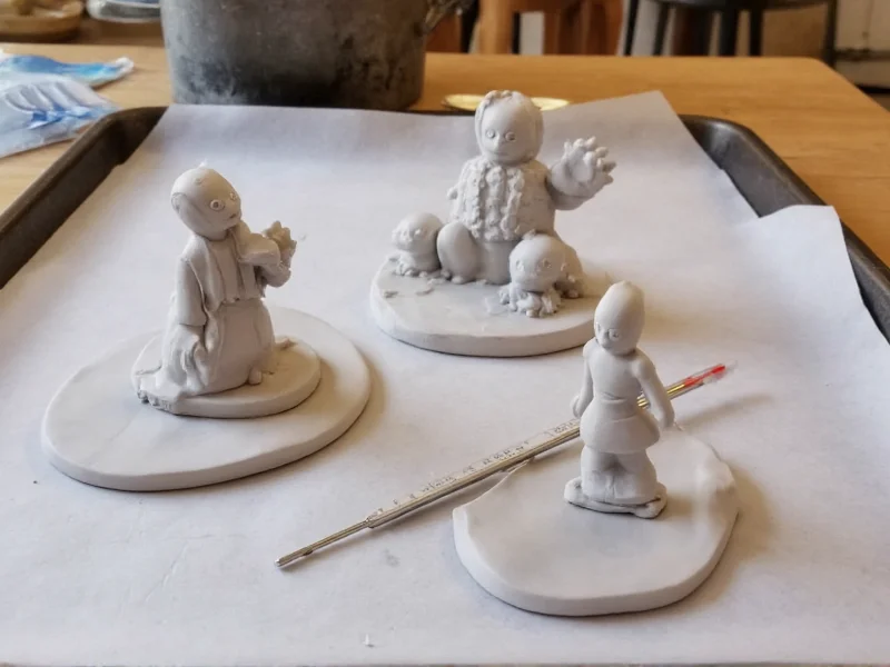 Polymer clay sculptures on baking sheet with thermometer