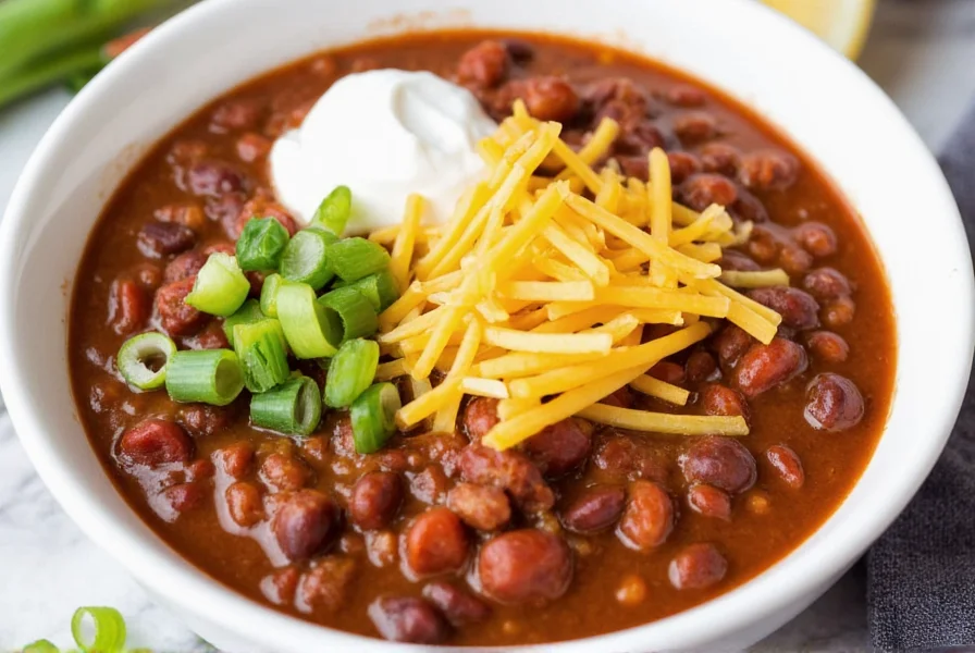 Bowl of simple chili recipe served with toppings including shredded cheese, sour cream, and green onions