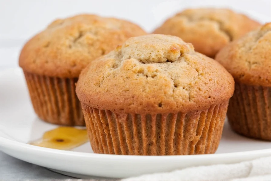 Close-up of golden brown cinnamon muffins with visible crumb structure and streusel topping on a white plate