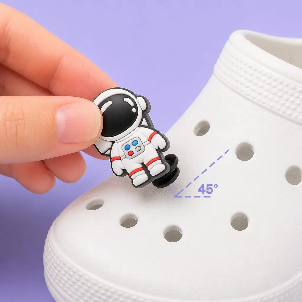 Hand inserting a space suited astronaut charm into a clog ventilation hole at a 45 degree angle