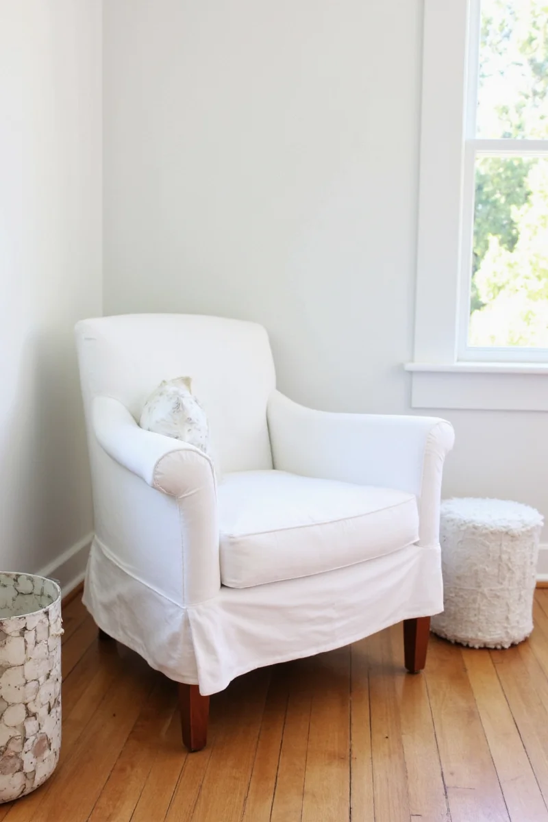 White slipcovered chair decorated with autumn throw pillows