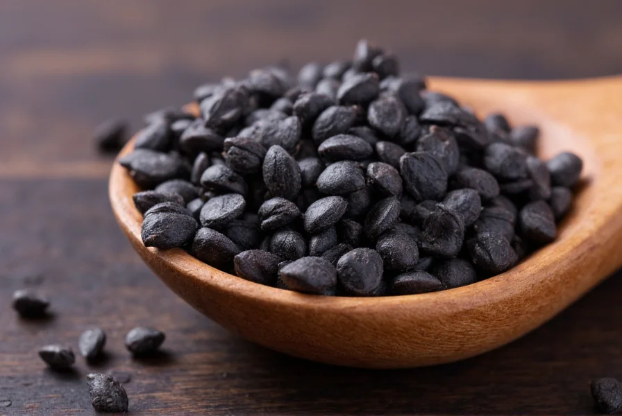 Close-up view of Nigella sativa seeds showing their triangular shape and matte black texture on a wooden spoon