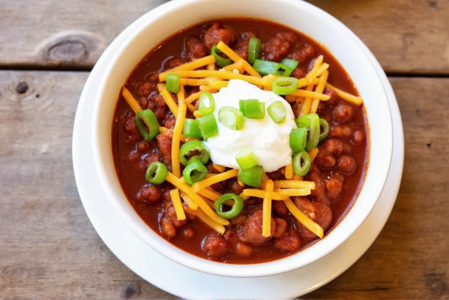 Finished bowl of homemade chili with toppings including shredded cheese, sour cream, and chopped green onions
