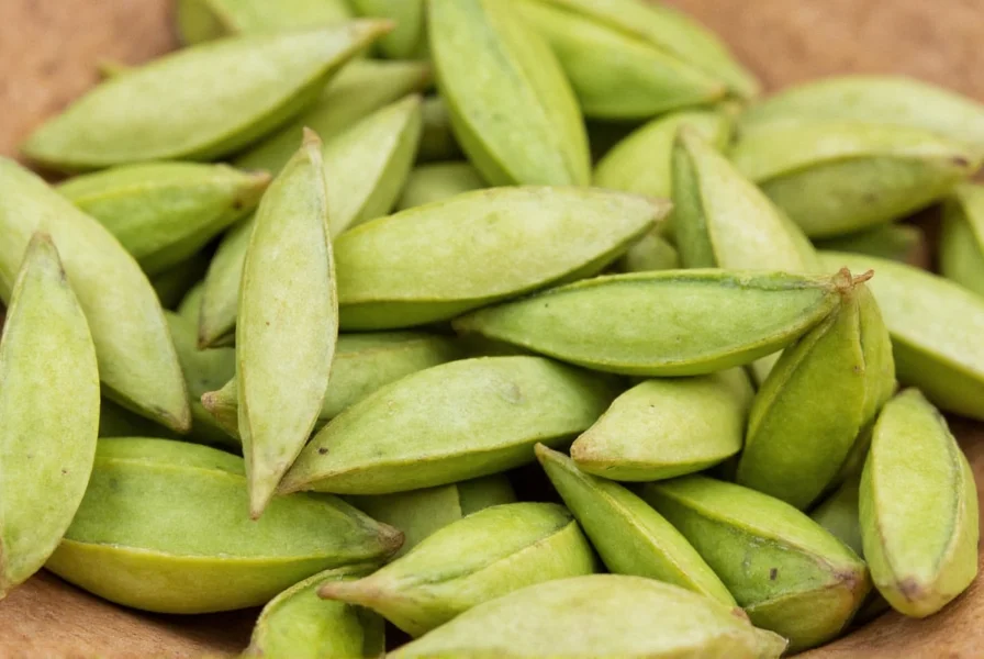 Close-up view of fresh green cardamom pods showing their triangular shape and pale green color against a wooden background