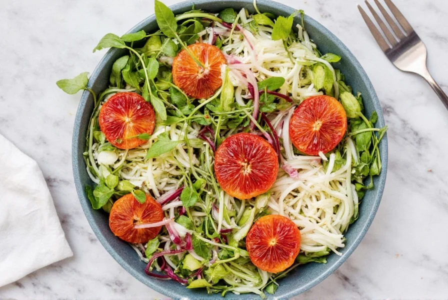 Colorful salad bowl featuring shaved fennel, blood oranges, and microgreens on marble surface