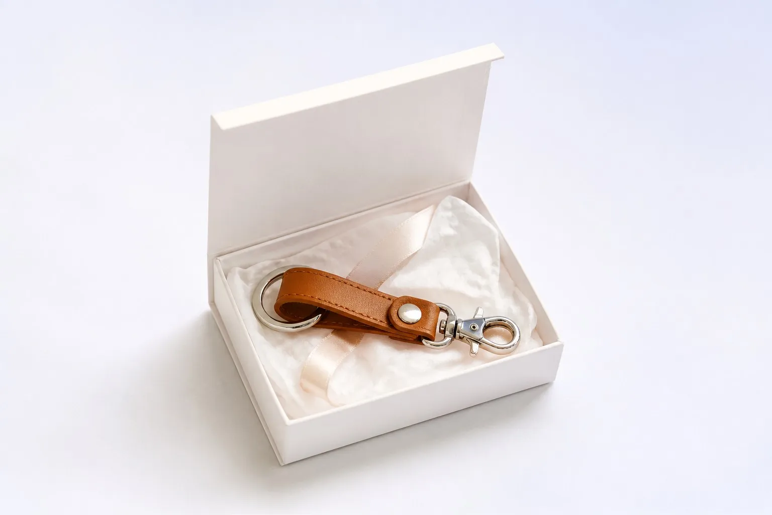 Leather keychain inside an open gift box with ribbon